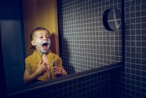 Маленький хлопчик голиться у дзеркалі і кричить — стокове фото