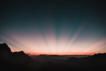 Scenic view to sunset beams in dusk sky over mountains — Stock Photo