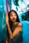 Nachdenkliche junge Frau lehnt an blauer Tür und schaut weg — Stockfoto
