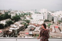 Frau posiert über Stadtbild und schaut weg — Stockfoto