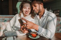 Abraçando casal usando smartphone no café na data — Fotografia de Stock