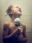 Jeune garçon chantant pour se doucher pendant le lavage dans la salle de bain . — Photo de stock