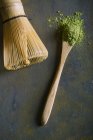 Bamboo scoop and whisk with matcha tea on stone surface — Stock Photo