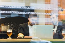 Geschäftsleute surfen mit Laptop hinter Café-Glas — Stockfoto