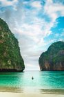 Вид сзади на человека, плывущего на лодке в тропическом заливе — стоковое фото