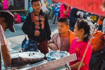 CHIANG RAI, THAILAND- FEVEREIRO 9, 2018: Jovens adolescentes asiáticos em pé na rua da cidade e comprando alimentos . — Fotografia de Stock