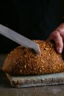 Мужские руки режут кусок хлеба — стоковое фото