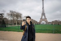 Joven turista tomando selfie en el fondo de la torre Eiffel . - foto de stock