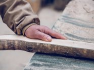 Mão de corte de carpinteiro trabalhando com pedaço de madeira na bancada — Fotografia de Stock
