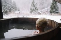 Blonde woman with short hair swimming in outside plunge tub in winter. — Stock Photo