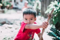 Laos, luang prabang: Kind sitzt auf dem Boden und spielt mit Stock — Stockfoto