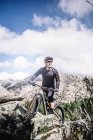 Зрелый байкер катается на велосипеде в горах в солнечный день — стоковое фото