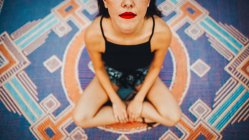 Зверху врожаю жінка з червоними губами сидить на килимі . — стокове фото