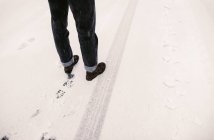 Crop person standing on road covered with snow in winter. — Stock Photo