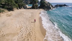 Вид с воздуха на женщину, бегущую по песчаному пляжу — стоковое фото