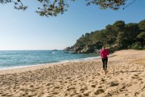 Vista posteriore della donna che fa jogging sulla spiaggia di sabbia — Foto stock