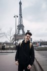 Jeune homme souriant posant sur fond de tour Eiffel . — Photo de stock
