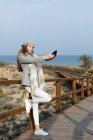 Fröhliche Frau macht Selfie mit Smartphone auf Uferpromenade — Stockfoto