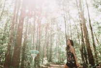Souriante jeune femme marchant dans la forêt par une journée ensoleillée . — Photo de stock