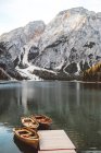 Vista al muelle de madera con botes amarrados en el lago de montaña - foto de stock