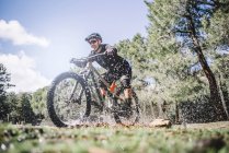 Зрілий велосипедист бризкає воду гірським велосипедом на природі — стокове фото