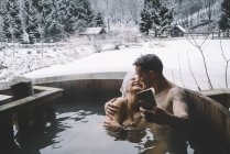 Paar umarmt sich in Badewanne im Freien und macht Selfie — Stockfoto