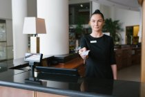 Hotelangestellte steht an der Rezeption und gibt Schlüssel ab — Stockfoto