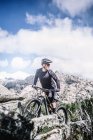Mature biker riding bike at mountains and looking back — Stock Photo