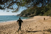 Вид человека, совершающего пробежку на песчаном пляже — стоковое фото