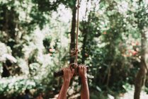 Crop mains de l'enfant accroché à la corde balançoire — Photo de stock
