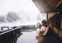 Casal sentado na banheira de mergulho ao ar livre e beijando — Fotografia de Stock
