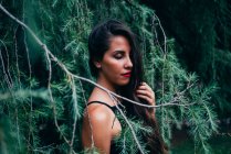 Pretty brunette woman posing in fir branches with eyes closed — Stock Photo
