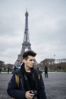 Jeune touriste avec caméra debout au-dessus de la tour Eiffel et regardant loin — Photo de stock