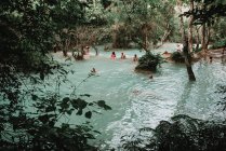 Laos, luang prabang: Menschen schwimmen im blauen Wasser des Waldsees. — Stockfoto