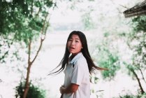 Laos, luang prabang: hübsche lokale Frau steht im grünen Wald und blickt über die Schulter in die Kamera. — Stockfoto