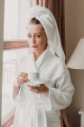 Thoughtful woman having coffee after bath — Stock Photo