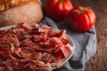 Still life of ham with tomatoes and bread — Stock Photo