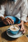 Обрезание женских рук, перемешивание чашки кофе на столе — стоковое фото