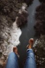 Looking down view of tourist sitting on edge over small river. — Stock Photo