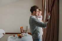 Young man with child looking at window — Stock Photo