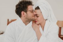 Sensual homem e mulher em roupões de banho abraçando na cama . — Fotografia de Stock