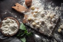 Directly above view of table with raw gnocchi on board and ingredients on table — Stock Photo