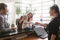Staff giving key to young family at hotel lobby — Stock Photo