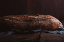 Rustic loaf of artisan bread on dark background — Stock Photo