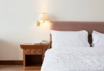 Ліжко і освітлені коліна в готельному номері — стокове фото