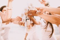 Group of pretty women friends standing together and pouring champagne in cloudy day. — Stock Photo