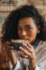 Портрет кудрявой женщины, пьющей кофе — стоковое фото