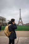 Visão traseira do jovem turista com câmera tirando fotos da torre Eiffel . — Fotografia de Stock