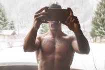 Oben-ohne-Mann steht in Badewanne und macht Selfie vor winterlichem Hintergrund. — Stockfoto