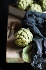 Bodegón de alcachofa cruda en la mesa - foto de stock